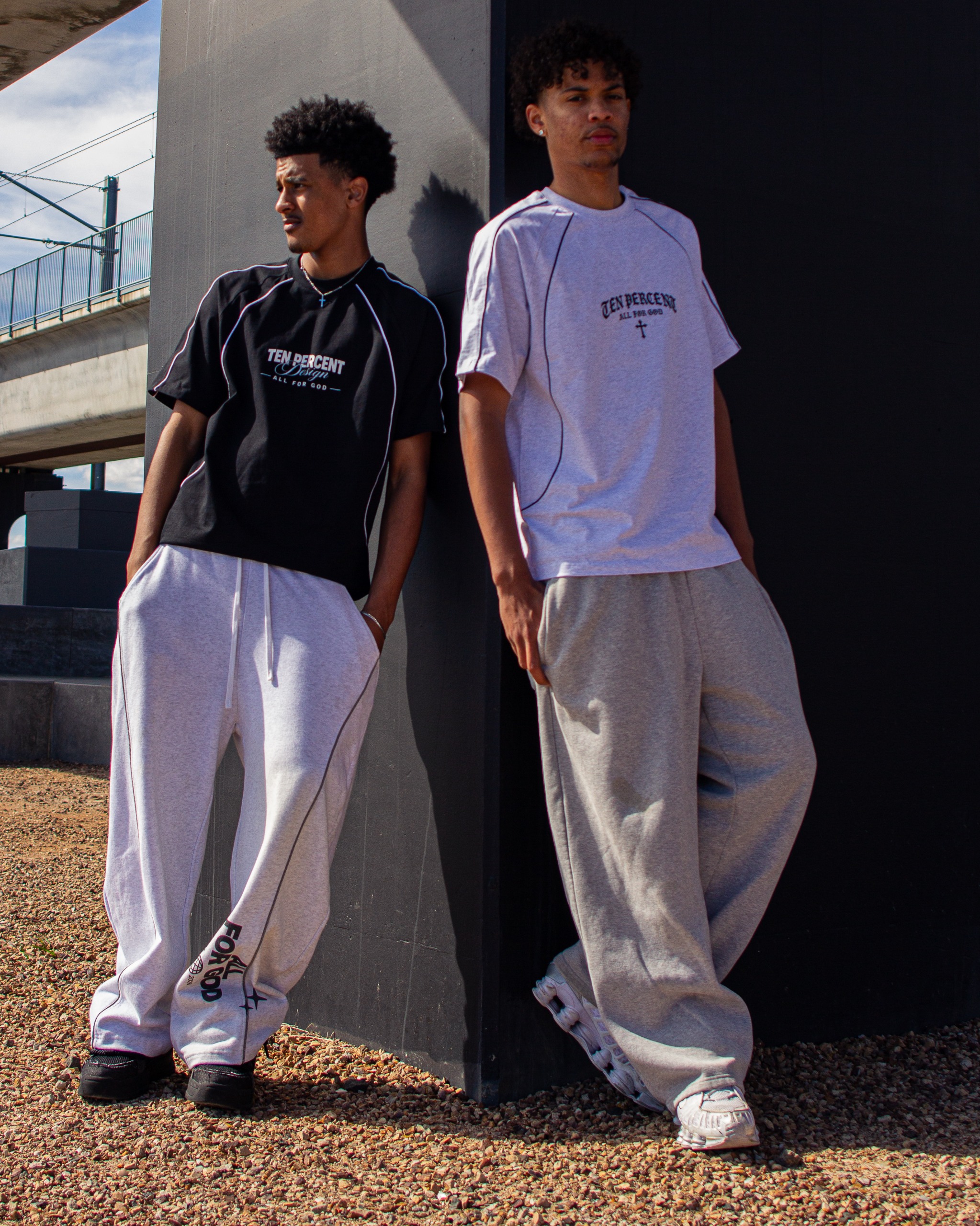 Person in a white hoodie and black sneakers standing against brick.